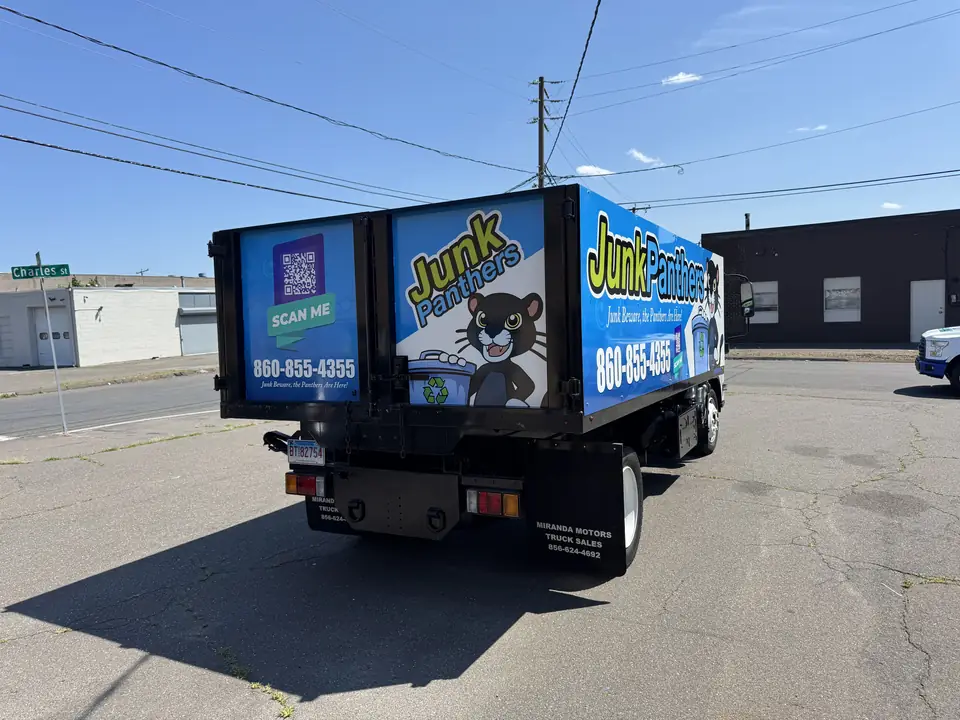 Junk Panthers dump truck with the panther mascot and phone number on the wrap